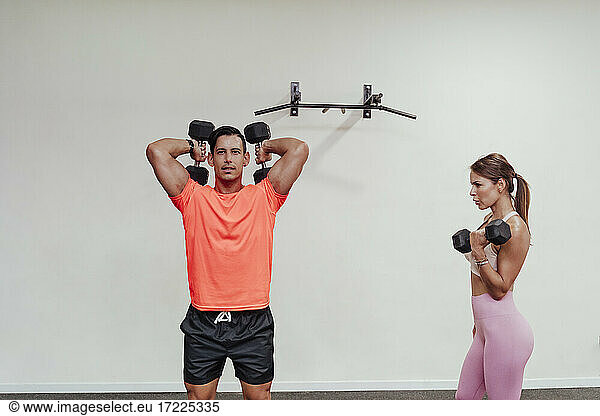 Männliche und weibliche Athleten trainieren mit einer Hantel im Fitnessstudio
