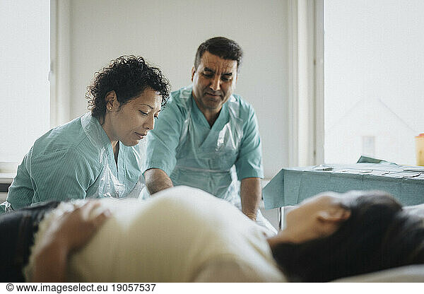 Männliche und weibliche Chirurgen bei der Untersuchung eines Patienten im Krankenhaus