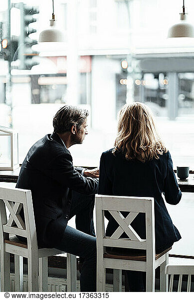 Männliche und weibliche Fachleute  die in einem Café zusammensitzen und diskutieren