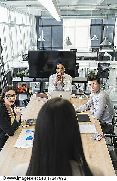 Männliche und weibliche Fachleute  die sich umsehen  und eine Geschäftsfrau  die während eines Treffens im Büro diskutiert