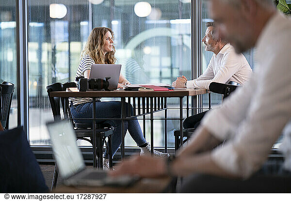 Männliche und weibliche Fachleute diskutieren am Tisch im Büro