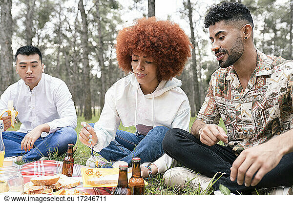 Männliche und weibliche Freunde essen Essen während einer Party im Wald