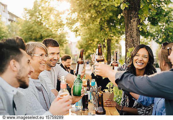 Männliche und weibliche Freunde lachen  während sie beim geselligen Beisammensein mit Getränken anstoßen