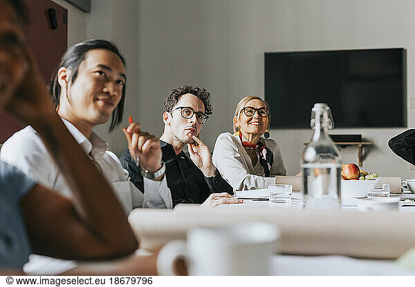 Männliche und weibliche Geschäftsleute  die an einer Sitzung im Sitzungssaal eines Büros teilnehmen