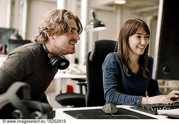 Männliche und weibliche lächelnde Fachleute diskutieren im Büro