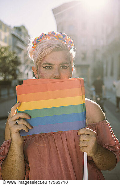 Männlicher Aktivist bedeckt Mund mit Regenbogenflagge