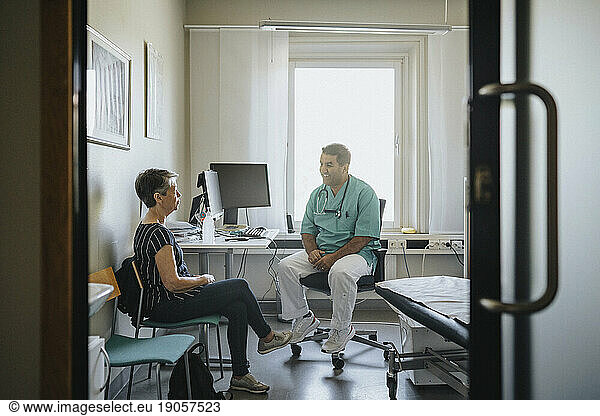 Männlicher Arzt im Gespräch mit einer älteren Frau in der Klinik