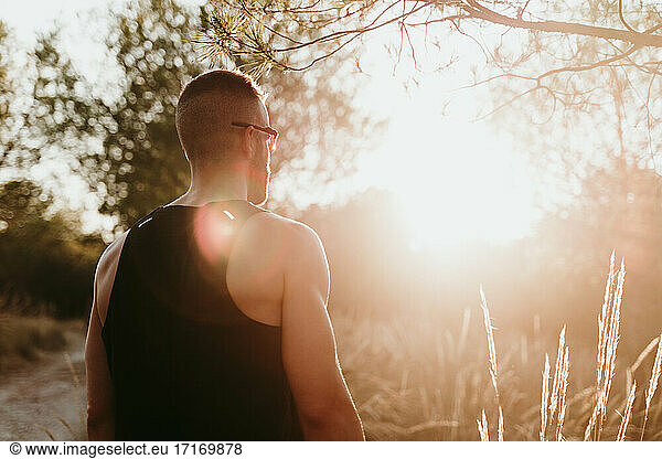 Männlicher Athlet bei Sonnenuntergang im Wald stehend