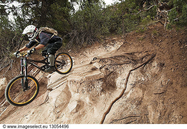 Männlicher Athlet beim Radfahren auf Felsen