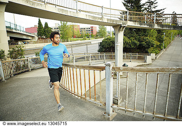 Männlicher Athlet joggt auf der Brücke
