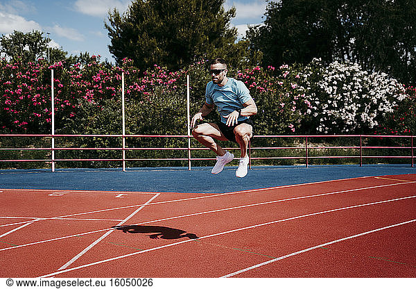 Männlicher Athlet springt auf Tartanbahn