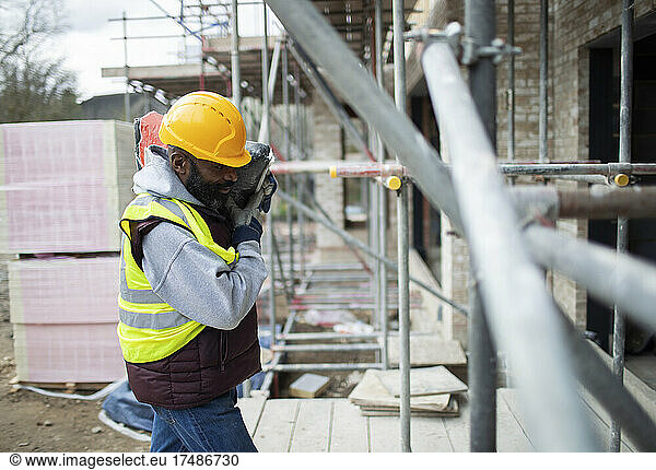 Männlicher Bauarbeiter trägt Ausrüstung auf der Baustelle
