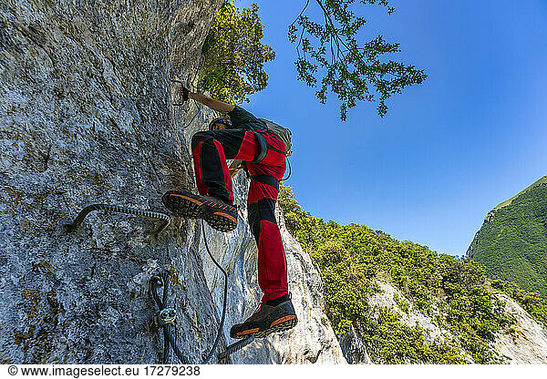 Männlicher Bergsteiger  der eine steile Wand im Apennin hinaufklettert