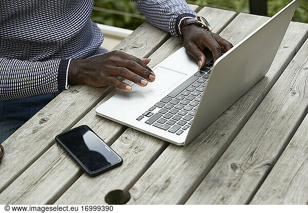Männlicher Berufstätiger mit Laptop am Holztisch