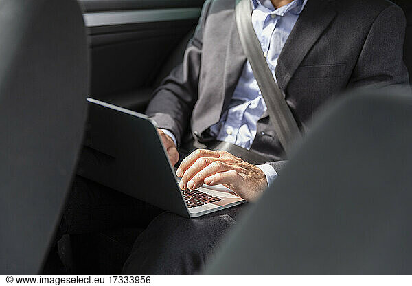 Männlicher Berufstätiger mit Laptop im Auto
