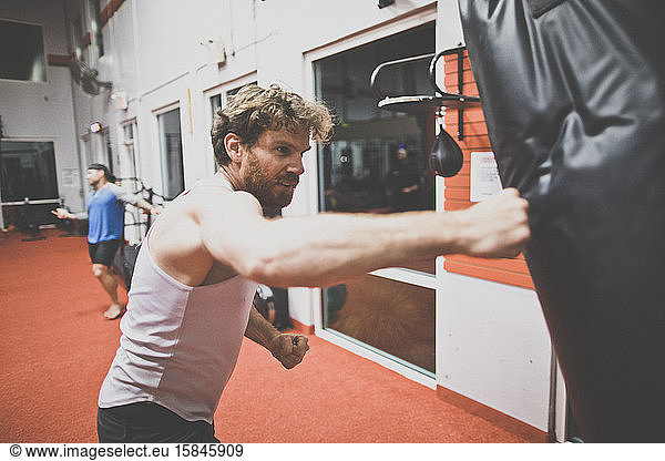Männlicher Boxer mit Boxsack in der Turnhalle