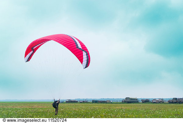Männlicher Fallschirmspringer landet auf Flugplatz