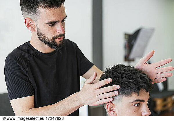 Männlicher Friseur bei der Frisur eines Kunden im Friseursalon