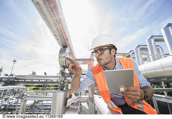 Männlicher Ingenieur  der ein Messgerät in einem geothermischen Kraftwerk kontrolliert
