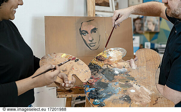 Männlicher Künstler unterrichtet eine Malerin im Malen