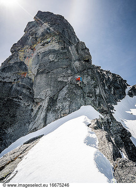 Männlicher Kletterer auf riesigem Gipfel im Schnee