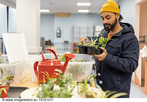 Männlicher Kunde mit Jacke beim Kauf von Pflanzen im Recyclingzentrum