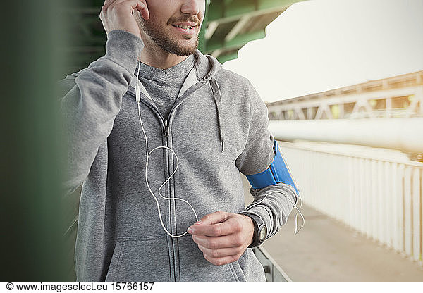 Männlicher Läufer  der mit Kopfhörern und mp3-Player Musik hört