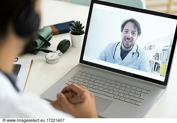 Männlicher Mitarbeiter im Gesundheitswesen bespricht sich per Videokonferenz mit einem Arzt