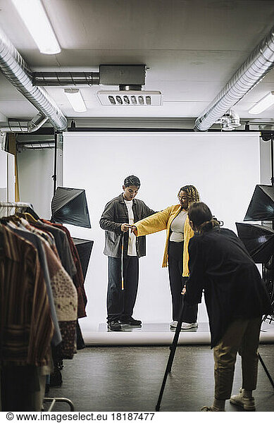 Männlicher Modedesigner  der ein Modell während eines Fotoshootings im Studio misst