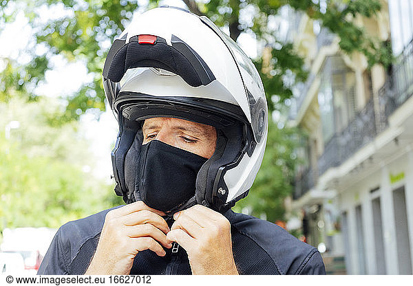 Männlicher Motorradfahrer beim Aufsetzen des Helms