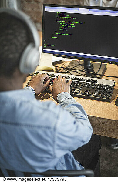 Männlicher Programmierer beim Programmieren am Computer in einem Start-up-Unternehmen