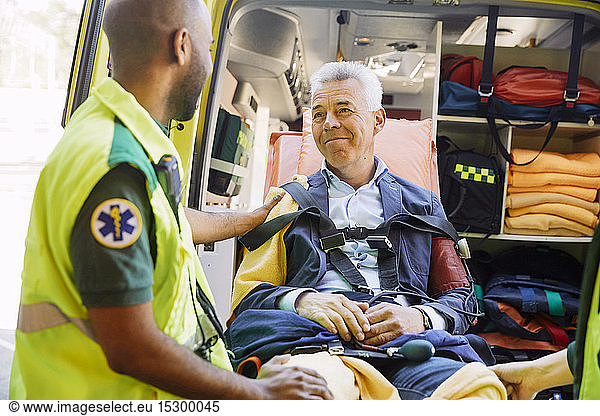 Männlicher Rettungssanitäter tröstet reifen Patienten im Krankenwagen