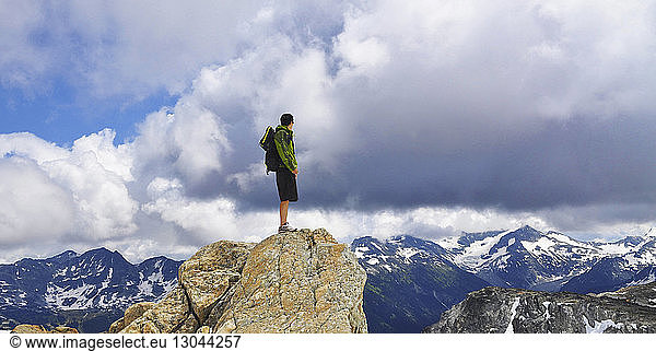 Männlicher Rucksacktourist steht auf Fels und schaut auf Sicht