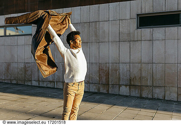 Männlicher Tänzer mit Jacke vor einem Gebäude