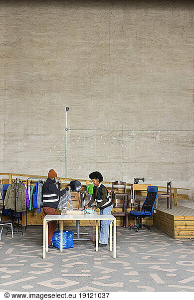 Männlicher und weiblicher Arbeiter helfen sich gegenseitig bei der Arbeit im Recyclingzentrum