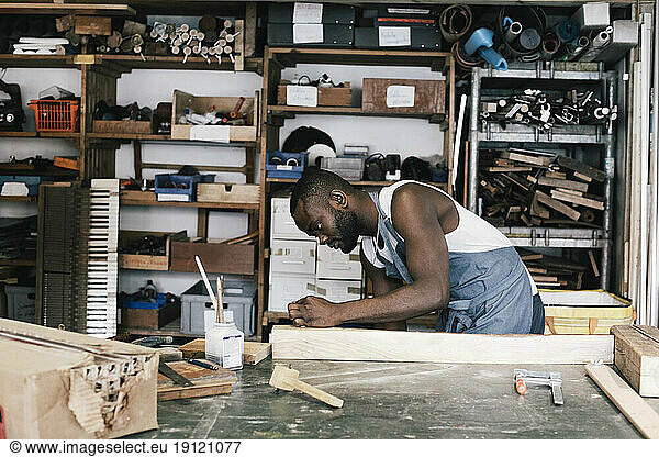 Männlicher Unternehmer beim Upcycling von Holz in der Werkstatt