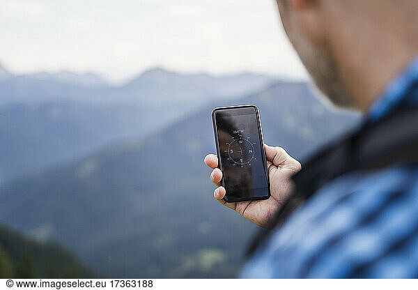 Männlicher Wanderer  der mit seinem Handy die Richtung sucht