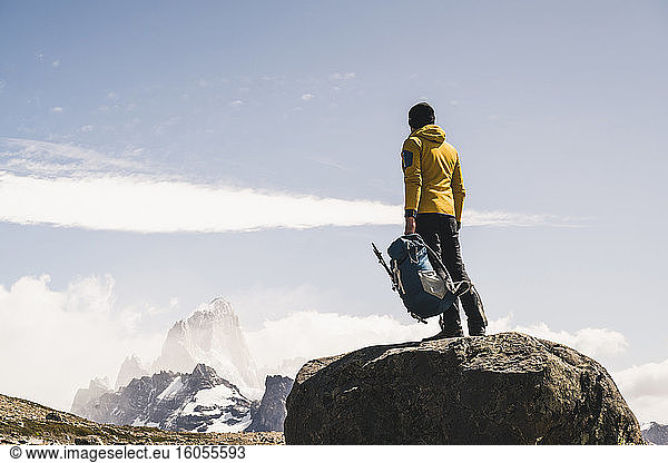 Männlicher Wanderer mit Rucksack auf einem Felsen stehend gegen den Himmel  Patagonien  Argentinien