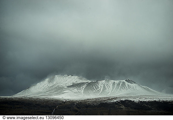 Majestätischer Blick auf schneebedeckte Berge vor stürmischen Wolken