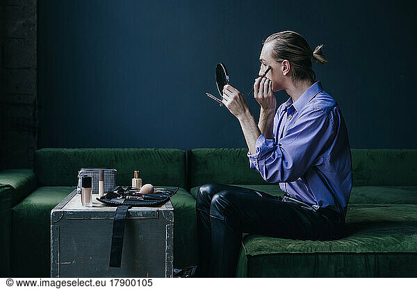 Make-up artist applying eyeshadow looking in hand mirror