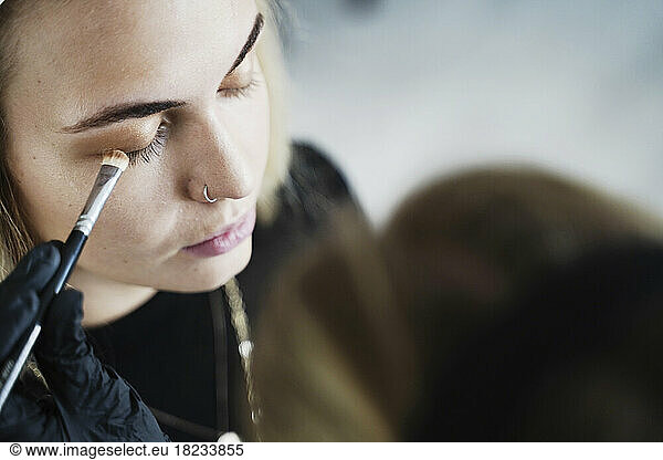 Make-up artist applying eyeshadow on customer's eye
