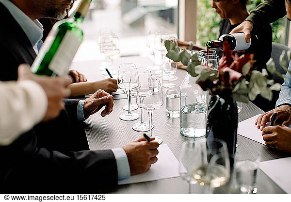 Male and business professionals with red wine at table in convention center