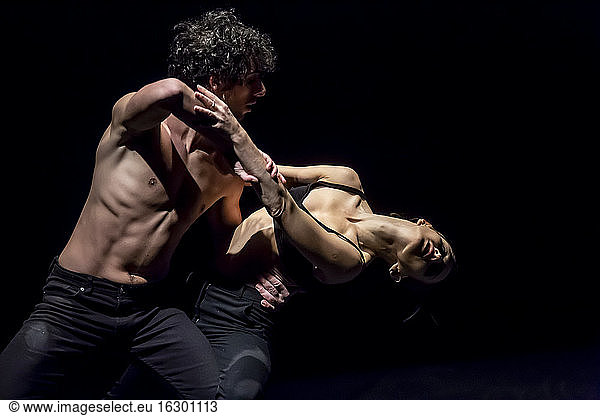 Male and femal dancer performing contemporary ballet on black stage