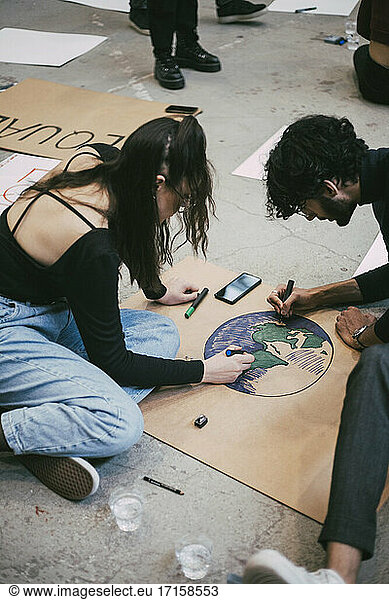 Male and female activists preparing signboard for environmental issue in building