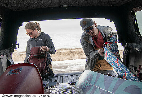 Male and Female Backcountry Snowboarders preparing gear at truck