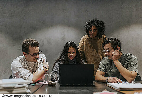 Male and female business colleagues discussing over laptop at conference table in startup company