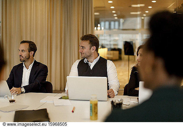 Male and female business professionals with laptop in meeting at office