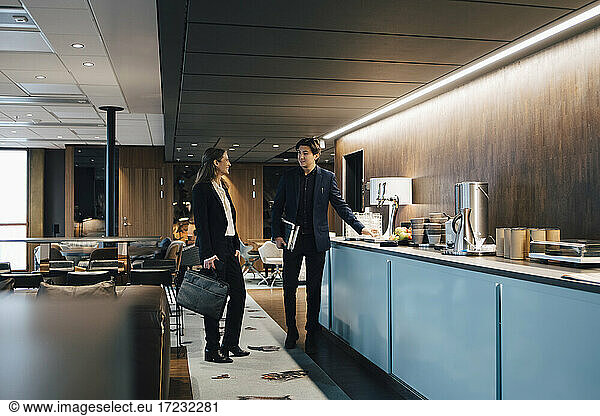 Male and female colleagues discussing in office cafeteria