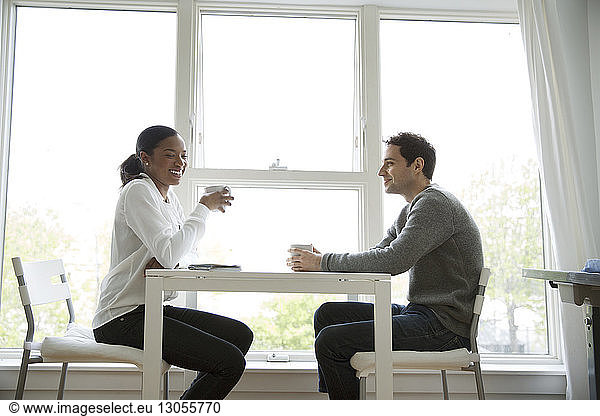 Male and female colleagues having coffee at table in office
