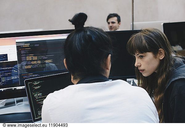 Male and female computer programmers discussing at office desk